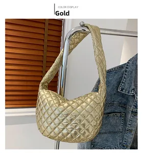 Detail of golden quilted crescent shoulder bag featuring metallic textured fabric