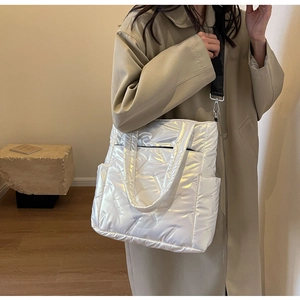 Quilted white pearl tote bag with adjustable black strap shown on model in a studio