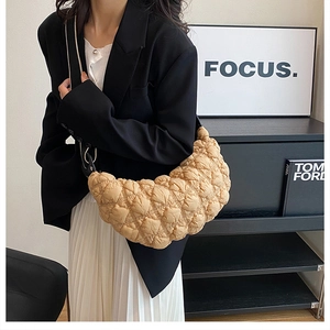 Borsa a mezzaluna beige trapuntata indossata da modella in un set interno minimalista