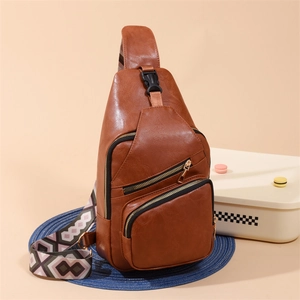 Detail of a brown PU leather crossbody bag featuring geometric patterned strap and zippers