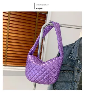Detail of purple quilted dumpling bag with metallic finish and wide shoulder strap