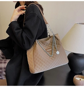 Détail d'un sac cabas en nylon matelassé marron avec chaîne argentée et étiquette en cuir