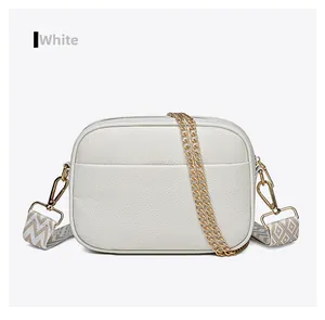 Close-up of white pebble leather crossbody camera bag with colorful patterned strap