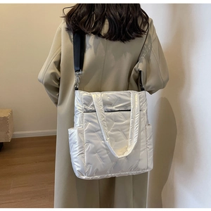 Detailed view of glossy white quilted crossbody bag with adjustable wide shoulder strap