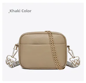 Detail of khaki pebbled leather camera bag with wavy strap and golden chain link