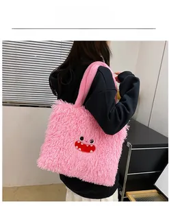Détail d'un sac cabas en peluche rose avec broderie de monstre porté par un mannequin