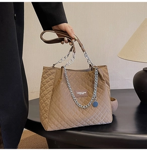 Détail du sac cabas matelassé en nylon marron foncé avec chaîne et écusson logo