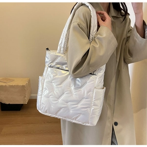 Detail of silver quilted tote bag showing padded nylon texture and side pocket