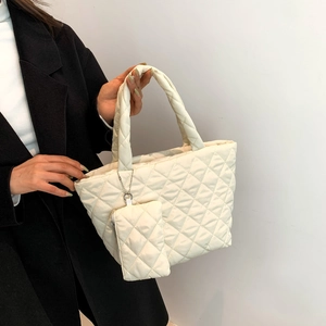 Winter minimalist cream quilted tote bag with matching charm on a model in a black coat