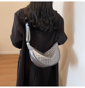 Silver quilted crescent bag with adjustable wide strap shown in a cross-body style
