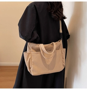Detail of beige corduroy tote bag showing ribbed texture and adjustable black strap