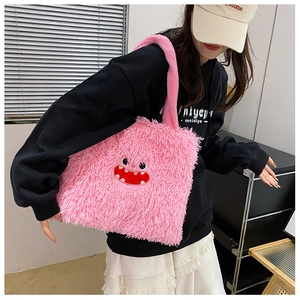 Sac fourre-tout en peluche rose avec patchs de monstre porté par un mannequin en tenue décontractée