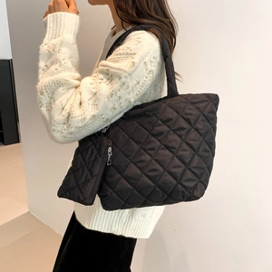 Quilted black nylon tote bag with matching zipper pouch shown on model shoulder