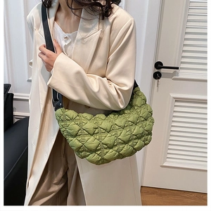 Dettaglio borsa hobo trapuntata verde chiaro con tracolla nera su cappotto bianco