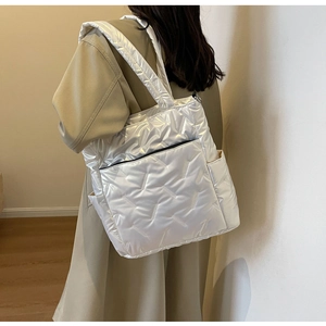 Detail of a white quilted tote bag with black zippers and lightweight padded texture