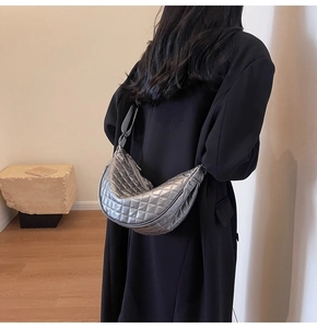 Rear view of model wearing a metallic silver quilted half-moon shoulder bag with wide strap