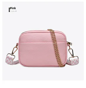 Detailed close-up of pink camera bag with lychee grain leather and gold metal chain