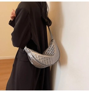 Close-up of a silver quilted crescent crossbody bag worn with a black blazer