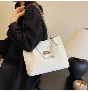 Détail du sac cabas matelassé blanc avec chaîne argentée porté par un mannequin en manteau