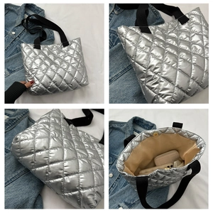 Detail view of silver quilted tote bag with black straps and spacious beige fabric lining