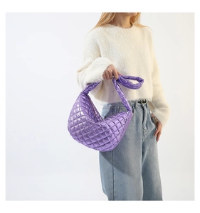 Close-up of a purple metallic quilted handbag with a crescent moon design and wide strap
