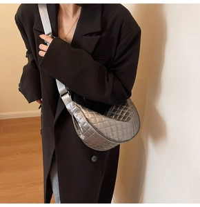 Detail of silver metallic quilted half-moon crossbody bag with adjustable nylon strap