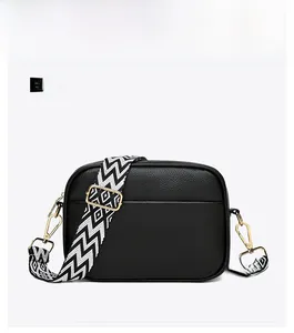 Detailed front view of black pebbled leather camera bag with a patterned woven strap