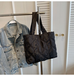 Close-up detail of black quilted tote bag with classic diamond stitch and soft silk finish