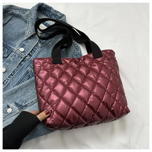 Detailed view of burgundy quilted tote bag with diamond stitching and black canvas handles