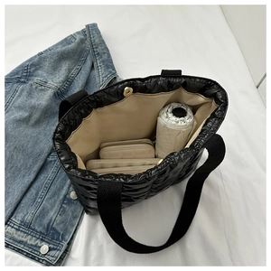 Detail view showing large interior space and magnetic closure of quilted puffer tote bag