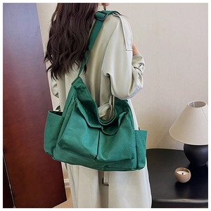 Detailed view of deep green canvas messenger bag with large front pockets and wide strap