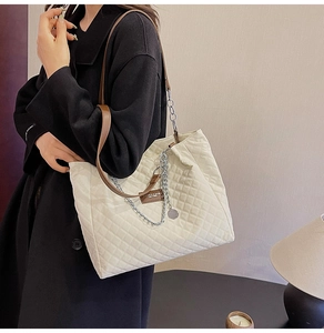 Sac fourre-tout beige matelassé avec chaîne et bandoulière en cuir sur manteau noir