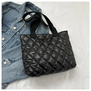 Flat lay of black quilted puffer tote bag with diamond stitching on blue denim jacket