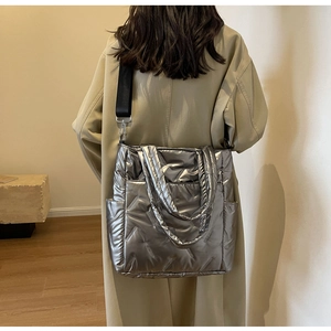 Detail of silver metallic quilted crossbody bag with adjustable wide black strap