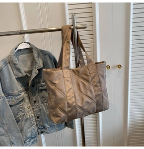 Detail of champagne quilted nylon tote bag with large diamond stitching and wide handles