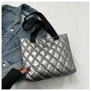 Macro detail of silver quilted tote bag with metallic finish and diamond stitching