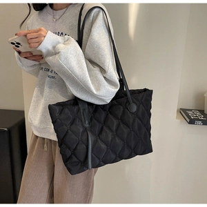 Nahaufnahme der schwarzen gesteppten Nylon-Einkaufstasche mit Fokus auf Textur und Träger