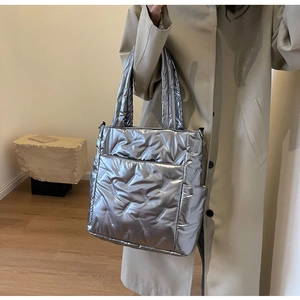 Close-up of silver metallic quilted tote bag with shiny finish and adjustable strap
