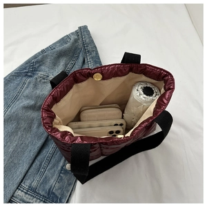Spacious interior of wine red quilted tote bag showing phones and a folding umbrella
