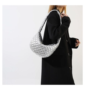 Quilted metallic silver puffer bag shown on a model with minimalist black coat