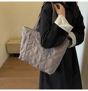 Detailed view of grey quilted tote bag with diamond stitching on glossy nylon fabric