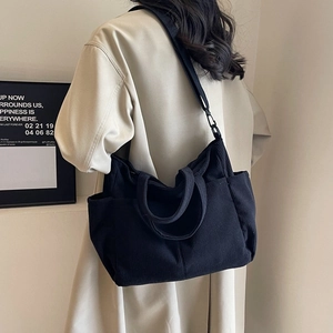 Minimalist black corduroy tote bag worn as a shoulder bag on a female model