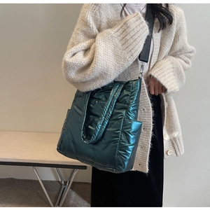 Detail of dark green quilted tote bag with metallic finish and wide nylon strap