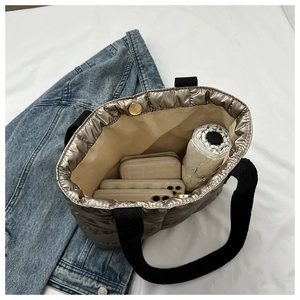 Spacious champagne quilted tote bag interior holding two phones, wallet, and umbrella