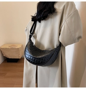 Detail view of black quilted crescent crossbody bag with wide adjustable shoulder strap