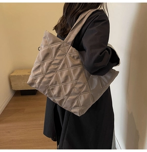 Macro detail of high-capacity quilted tote bag in grey-brown nylon with wide strap
