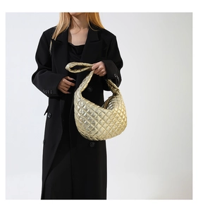 Detail showing metallic gold quilted PU handbag worn over a black coat with sleek textures