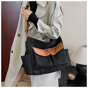 Close-up of black canvas messenger bag with brown flap pockets and adjustable strap
