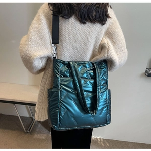 Detail of dark green quilted tote bag with silver hardware and black nylon strap