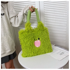 Gros plan sur le sac à main en peluche verte avec broderie de visage de monstre rose